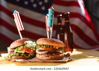 three fresh and juicy burgers with American flag-style fireworks inserted into them. bbq concept picnic to celebrate independence day
