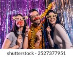 Three friends celebrating New Years Eve at the night club. They put on funny goggles and mustache.