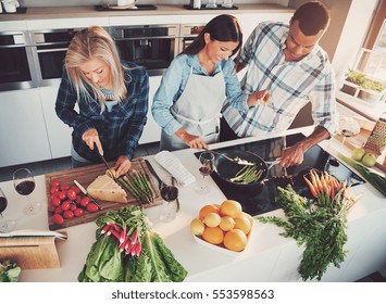 Three Friends Cooking At Kitchen Clearly Having Fun, Shot From Above