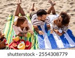 Three friends drink colorful healthy fruit juices at the picnic on the beach.