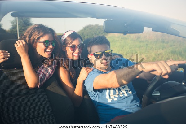 Three friends driving around in a convertible\
exploring pointing at\
something