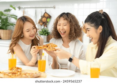 Three friends enjoying a delicious pizza meal together, laughing and drinking orange juice in a sunlit kitchen. - Powered by Shutterstock