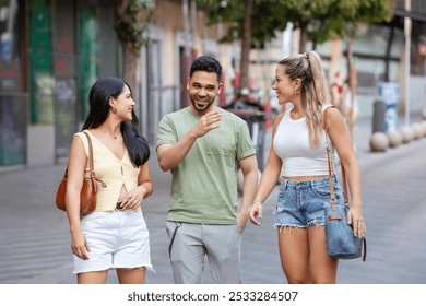 Three friends are enjoying a summer day walking down a city street, laughing and chatting as they go - Powered by Shutterstock