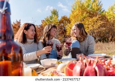 Three friends had a picnic in the autumn field. 3 young women beautifully eat and drink wine. Girlfriend concept. Autumn forest.