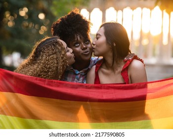 Three Friends Kissing With Gay Pride Flag, Lgbt Rainbow, Happy Women Kissing And Wearing Rainbow Flag Outdoors - Love And Lesbian Sunset Concept - Soft Focus -