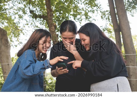 Three friends laugh and giggle over a funny video playing on their cellphone while at the park. Stock foto © 