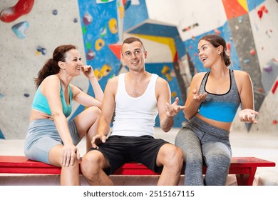 Three friends, man and woman, discuss their climbs on climbing wall without safety net, sitting on bench in a recreation area - Powered by Shutterstock