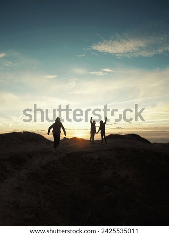 Three friends on the beach dunes with the sunset in the background. 