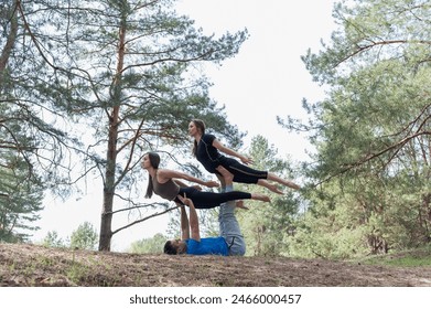 Three friends practice acro yoga exercises while hiking in the forest. - Powered by Shutterstock