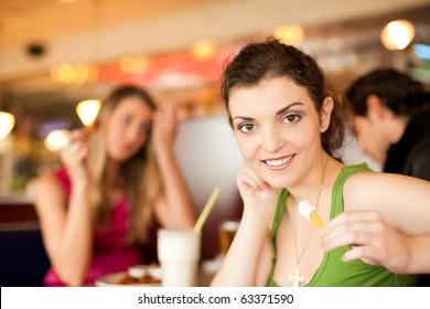 Three Friends In A Restaurant Or Diner Eating Fries And Drinking Milkshakes, Shot With Available Light, Very Selective Focus