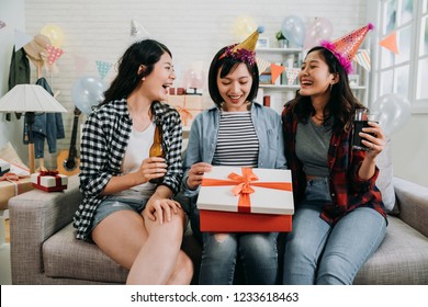 Three Friends Sharing Happy Moments Opening Birthday Present. Young Asian Girl Curiously Looking Inside Gift Box. Beautiful Ladies Giving Surprise And Drinking Beer Love Alcohol.