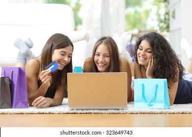 Three Friends Shopping Online With Credit Card And Laptop Lying On The Floor At Home