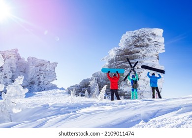 Three friends snowboarders, skier stands with ski and snowboard background blue sky with sun light. Concept extreme freeride Sheregesh resort.