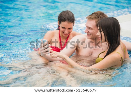 three friends taking selfie in the swimming pool. Concept about friendship, people,technology and fun