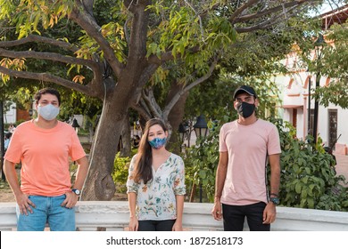 Three Friends Talking And Having Fun At The Park Outdoors Wearing Face Masks And Respecting Social Distancing During A Pandemic