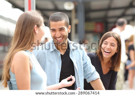 Three friends talking and laughing taking a conversation in a train station