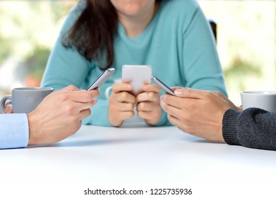 Three friends using their smart phones in a bar