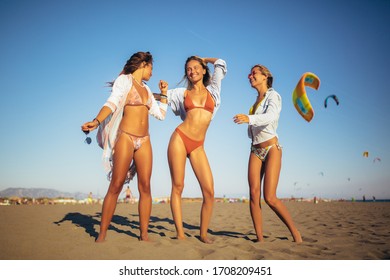 Three friends walking on the beach and laughing on a summer day, enjoying vacation. - Shutterstock ID 1708209451