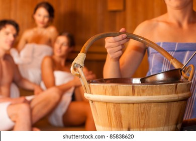 Three friends - three women, one man - doing wellness in the sauna of a thermal bath