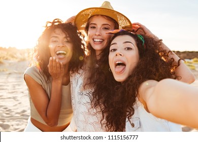 Three funny girls friends in summer clothes taking a selfie at the beach - Powered by Shutterstock