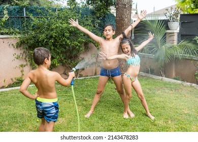 Three Funny Kids Playing With A Hose In The Garden