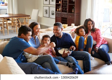 Three generation African American family   sitting on the sofa in living room, watching TV and eating popcorn together, elevated view - Powered by Shutterstock