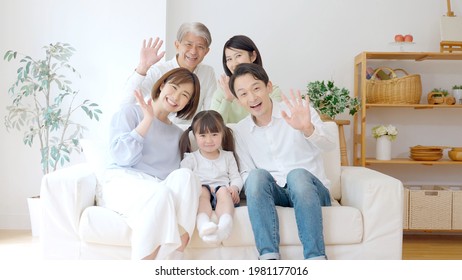 Three Generation Asian Family Waving Hands In The Living Room