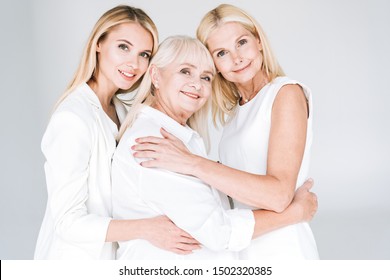 three generation blonde women embracing isolated on grey