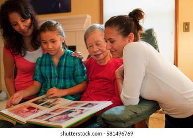 Three Generation Family Looking At Photo Album