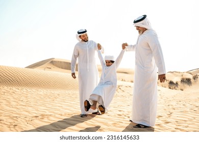 Three generation family making a safari in the desert of Dubai wearing white kandura outfit. Grandfather, son and grandson spending time together in the nature. - Powered by Shutterstock