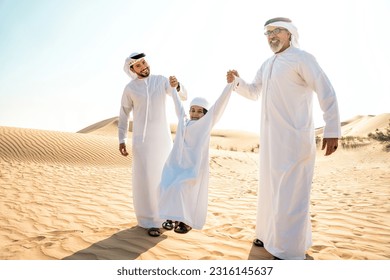 Three generation family making a safari in the desert of Dubai wearing white kandura outfit. Grandfather, son and grandson spending time together in the nature. - Powered by Shutterstock