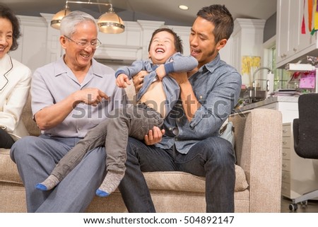 Three generation family playing with young boy on sofa