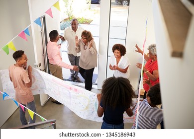 Three Generation Family Throwing A Surprise Party Welcoming Guests At The Front Door,elevated View