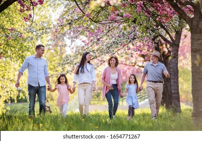 Three generation family walking outside in spring nature.