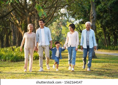 three generation happy asian family walking outdoors in park