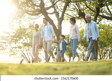 three generation happy asian family walking outdoors in park - Shutterstock ID 1562170600