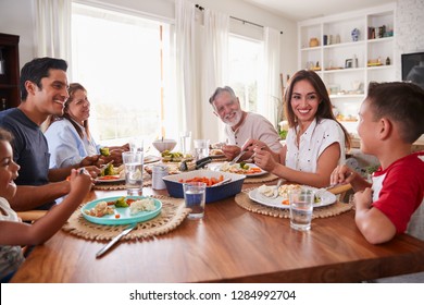 Three Generation Hispanic Family Sitting At The Table Eating Dinner