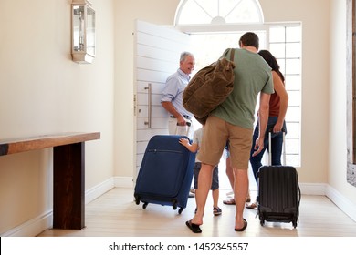 Three generation white family leaving their home to go on holiday together, full length, back view
