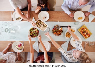 Three Generation White Family Sitting At A Dinner Table Together Serving A Meal, Overhead View