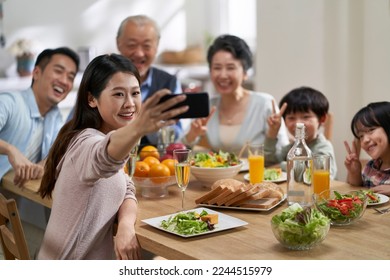 three generational asian family taking a selfie while having meal together - Powered by Shutterstock