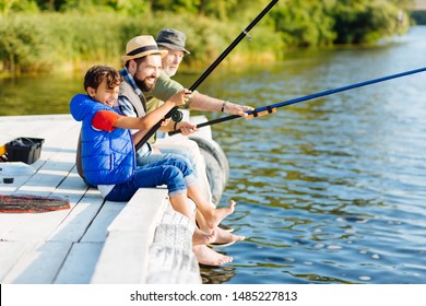 Three generations. Beaming cheerful men of three generations feeling happy while fishing in summer