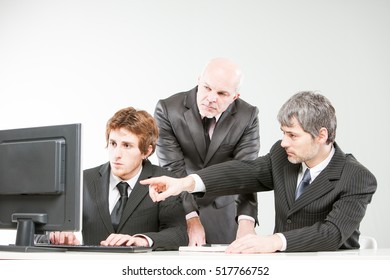 Three Generations Of Business Men Watching Something On The Screen Of A Personal Computer