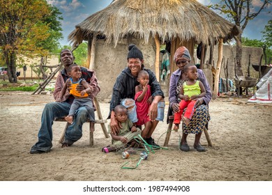 Three Generations Extended African Family In Front Of Their Thatched Roof Hut, Village In Botswana