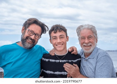 Three generations of family men, hugging smiling happy, father, teenage son and grandfather. Handsome people relaxing together - Powered by Shutterstock