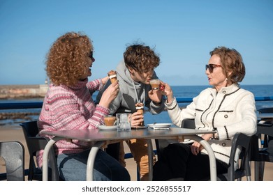 Three generations family sharing ice cream and coffee at a seaside café - Powered by Shutterstock