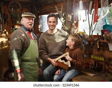 Three generations - father, grandfather and son are working on a wooden bird house. They are in the grandfather workshop, he is wearing a green apron and several tools are hanging from the ceiling - Powered by Shutterstock