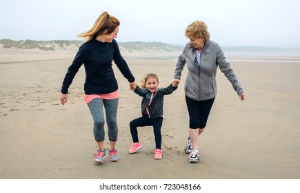 Three Generations Female Running On The Beach In Autumn