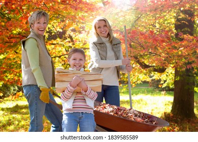 Three generations of ladies doing yard work on a sunny autumn day with the girl holding a log of wood in her hands while her mother and grandmother are collecting leaves. - Powered by Shutterstock