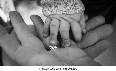 Three generations of men father baby son and grandfather hands together in black and white family photo