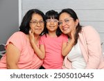 Three Generations of women Grandmother, mom and brunette Latina daughter with glasses show their love and celebrate Mother